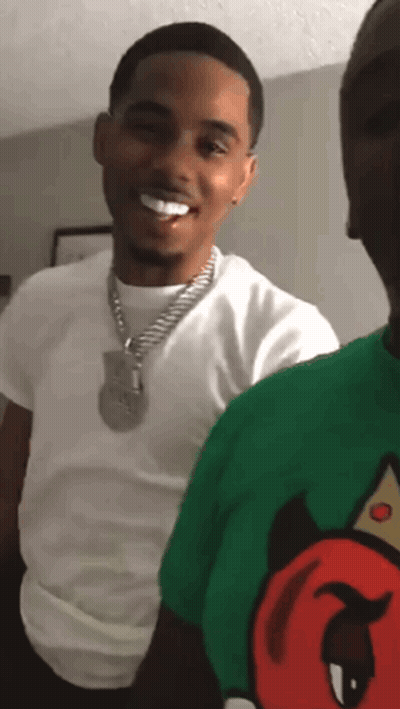 A Man In A White Shirt And A Green Shirt With A Devil On It Smiles GIF