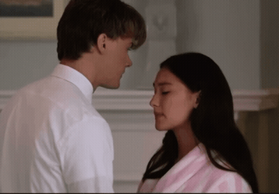 A Man In A White Shirt And A Woman In A Pink Robe Are Looking Into Each Other 'S Eyes GIF