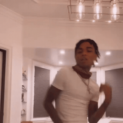 A Man In A White Shirt And Bandana Is Dancing In A Living Room . GIF