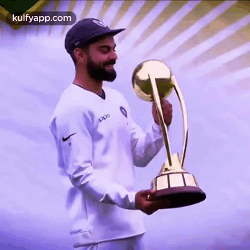 A Man In A White Shirt And Black Hat Is Holding A Trophy . GIF
