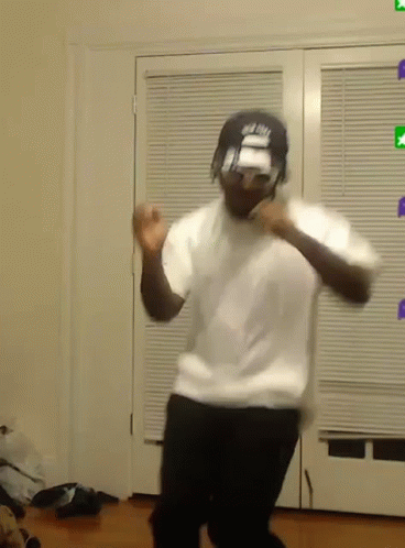 A Man In A White Shirt And Black Pants Is Dancing In A Living Room . GIF