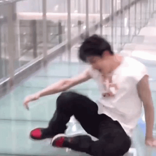 A Man In A White Shirt And Black Pants Is Falling Down A Glass Floor . GIF