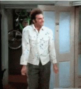 A Man In A White Shirt And Black Pants Is Standing In A Doorway . GIF