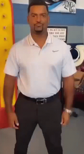 A Man In A White Shirt And Black Pants Is Standing In Front Of A Sign That Says Palace Is Not A Public Place GIF