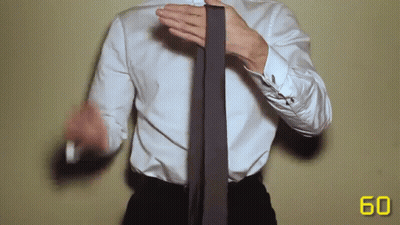 A Man In A White Shirt And Black Pants Is Tying A Tie GIF