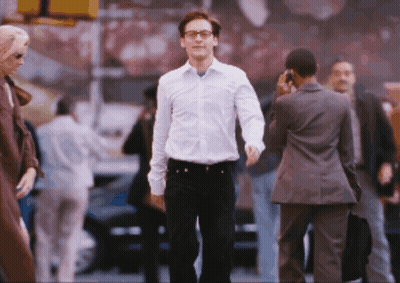 A Man In A White Shirt And Black Pants Walks Down A Street GIF