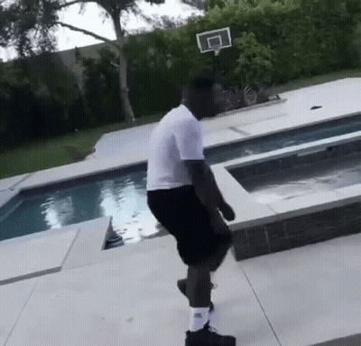 A Man In A White Shirt And Black Shorts Is Standing Next To A Swimming Pool GIF