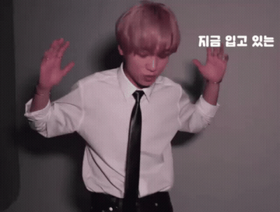 A Man In A White Shirt And Black Tie Is Dancing In Front Of A Wall With Chinese Writing On It GIF