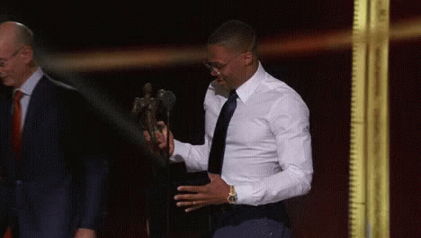 A Man In A White Shirt And Black Tie Is Holding A Trophy . GIF