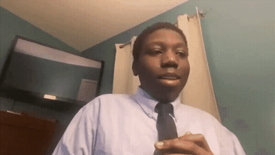 A Man In A White Shirt And Black Tie Is Standing In Front Of A Flat Screen Tv GIF