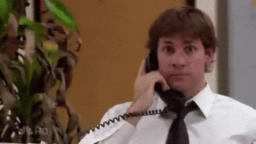 A Man In A White Shirt And Black Tie Is Talking On A Phone . GIF