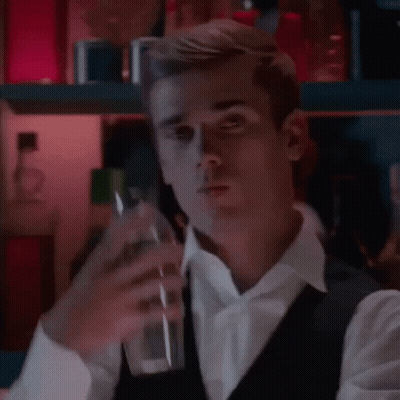A Man In A White Shirt And Black Vest Is Holding A Glass Of Water . GIF