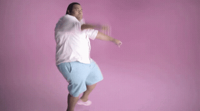 A Man In A White Shirt And Blue Shorts Is Jumping In The Air . GIF