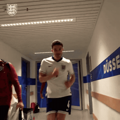 A Man In A White Shirt And Blue Shorts Is Running In A Hallway With Dusse Written On The Wall GIF