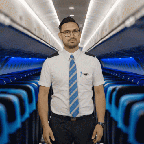 A Man In A White Shirt And Blue Tie Is Standing In A Plane GIF