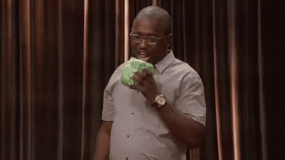 A Man In A White Shirt And Glasses Is Eating A Piece Of Cabbage . GIF