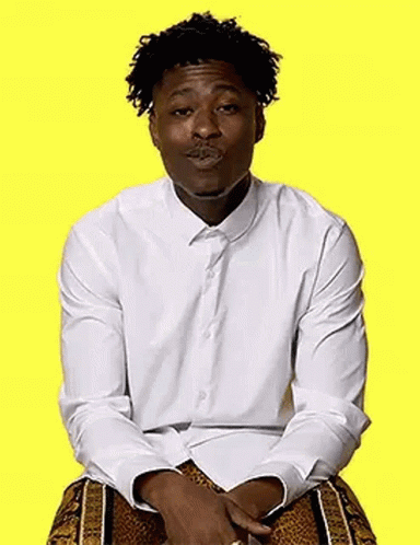 A Man In A White Shirt And Leopard Print Shorts Is Sitting On A Yellow Background And Making A Funny Face . GIF