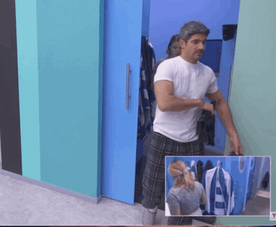 A Man In A White Shirt And Plaid Pants Stands In A Room GIF