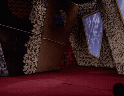 A Man In A White Shirt And Red Pants Is Jumping In The Air In A Room GIF