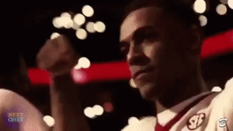 A Man In A White Shirt And Red Tie Is Standing In Front Of A Crowd With His Fist In The Air . GIF