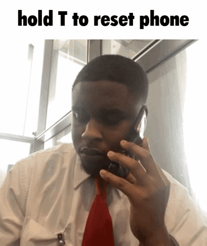 A Man In A White Shirt And Red Tie Talking On A Cell Phone With The Words Hold T To Reset Phone Above Him GIF