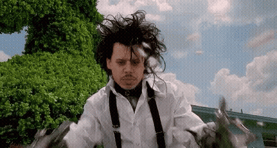 A Man In A White Shirt And Suspenders Is Holding Scissors In His Hands . GIF