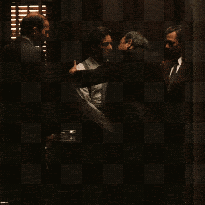 A Man In A White Shirt And Suspenders Is Shaking Hands With Another Man GIF