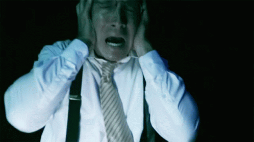 A Man In A White Shirt And Tie Covering His Ears GIF