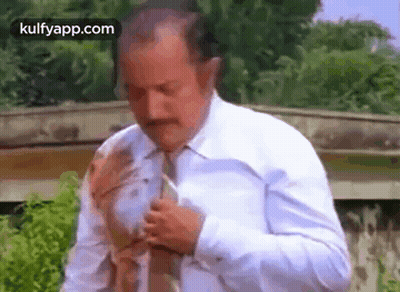 A Man In A White Shirt And Tie Is Getting Ready To Go Out . GIF