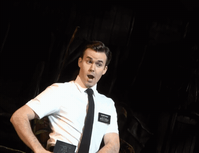 A Man In A White Shirt And Tie Is Laughing While A Woman Stands Behind Him GIF