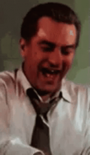 A Man In A White Shirt And Tie Is Laughing While Holding A Piece Of Paper . GIF