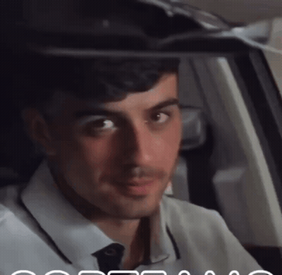 A Man In A White Shirt And Tie Is Looking Out The Window GIF