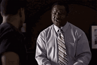 A Man In A White Shirt And Tie Is Shaking Hands With Another Man And Says She . GIF