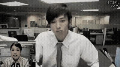 A Man In A White Shirt And Tie Is Sitting In Front Of A Woman In An Office Cubicle . GIF