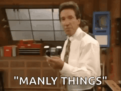 A Man In A White Shirt And Tie Is Standing In An Office Holding A Cell Phone And Saying `` Manly Things '' . GIF