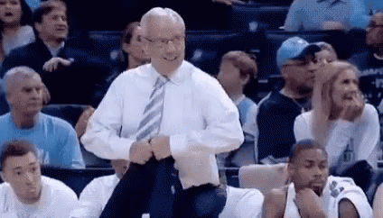 A Man In A White Shirt And Tie Is Standing In Front Of A Crowd Of People . GIF