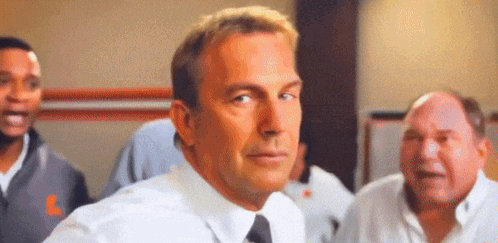 A Man In A White Shirt And Tie Is Standing In Front Of A Group Of People . GIF