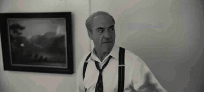 A Man In A White Shirt And Tie Is Standing In Front Of A Painting . GIF