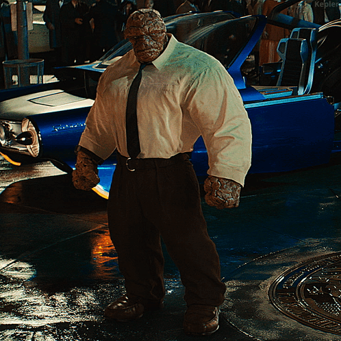 A Man In A White Shirt And Tie Stands In Front Of A Blue Car That Says Kepler GIF