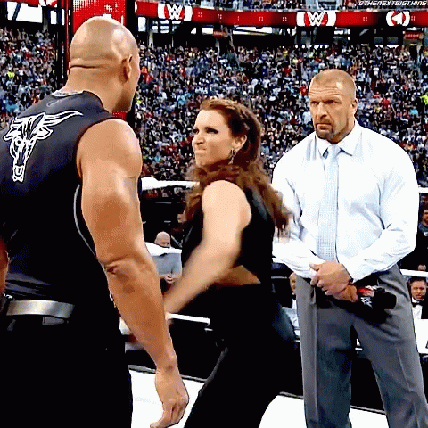 A Man In A White Shirt And Tie Stands Next To A Woman In A Black Tank Top With A Bull On It GIF