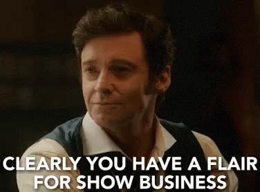 A Man In A White Shirt And Vest Is Smiling And Says `` Clearly You Have A Flair For Show Business '' . GIF