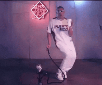 A Man In A White Shirt And White Pants Is Dancing In Front Of A Microphone . GIF