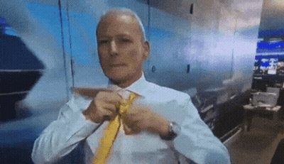 A Man In A White Shirt And Yellow Tie Is Tying His Tie . GIF