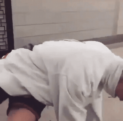 A Man In A White Shirt Is Bending Over And Looking Down . GIF