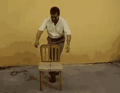 A Man In A White Shirt Is Carrying A Black Box On His Back GIF