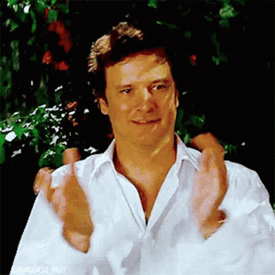 A Man In A White Shirt Is Clapping His Hands In Front Of A Tree . GIF