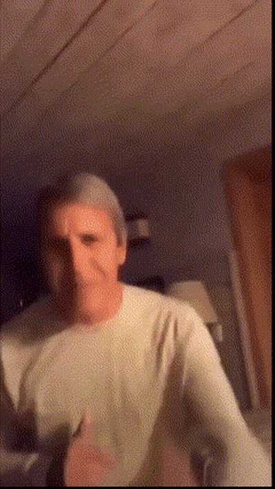 A Man In A White Shirt Is Dancing In A Dark Room . GIF