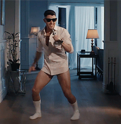 A Man In A White Shirt Is Dancing In A Hallway GIF