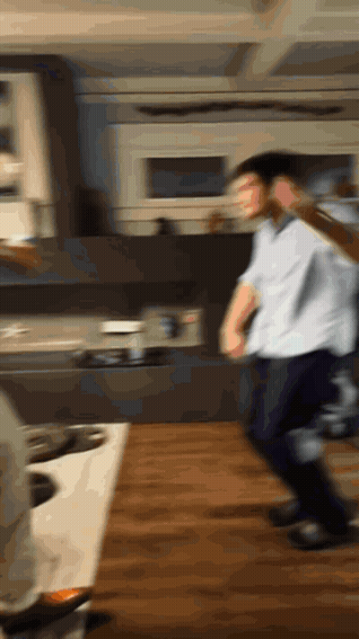 A Man In A White Shirt Is Dancing In A Kitchen GIF
