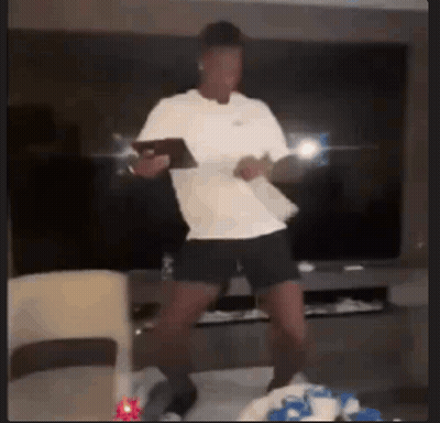 A Man In A White Shirt Is Dancing In A Living Room While Holding A Tablet . GIF